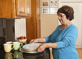 Woman at the kitchen counter lifting a clean plate.