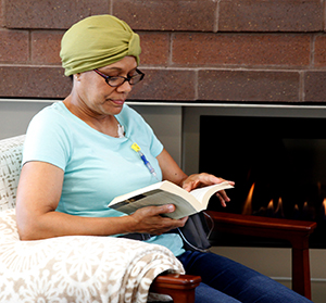 Woman sitting at home reading, with chemo infusion port in chest.