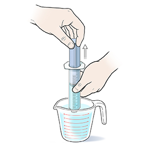 Closeup of hands drawing water into syringe from measuring cup.