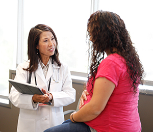 Pregnant woman in an exam room talking with a healthcare provider