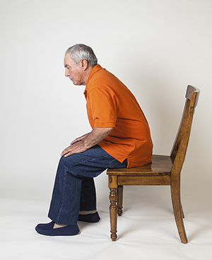 Man sitting at front edge of chair, getting ready to stand up.