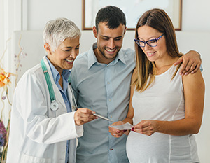 Doctor having conversation with pregnant couple.