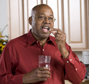 Hombre que toma una pastilla con un vaso de agua.